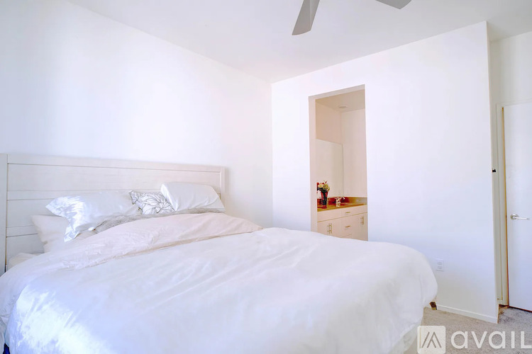 A bedroom with a large bed and a small dresser with a mirror.
