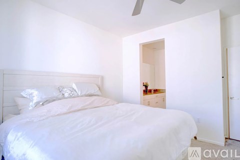 A bedroom with a large bed and a small dresser with a mirror.