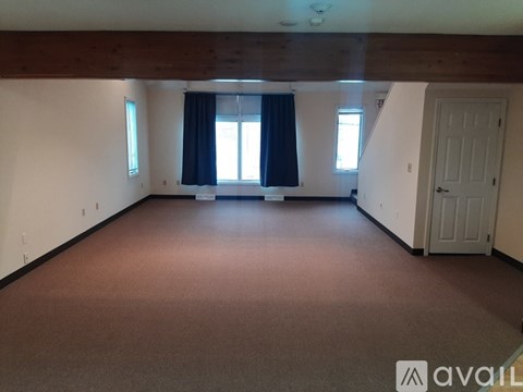 A large empty room with a window and a door.