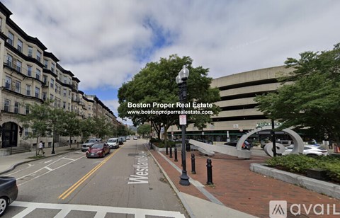 A street view of a residential area with apartment buildings on the left and a street with cars parked on the side.