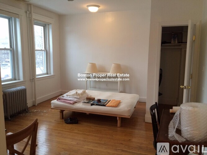 A bedroom with a bed, chair, and window.