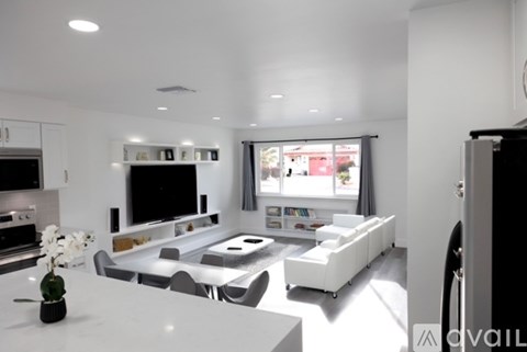 A modern living room with a white sofa set and a television.