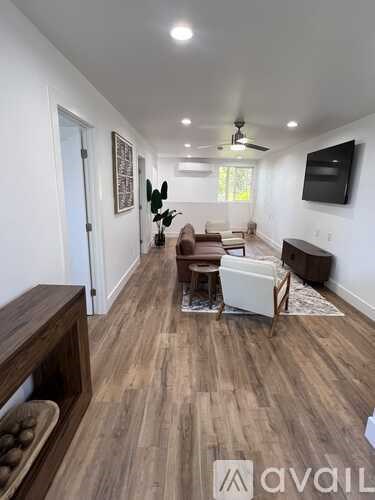 A living room with a brown sofa and a television mounted on the wall.