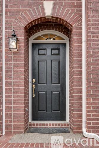 A black door with a gold handle and a lantern on the wall.
