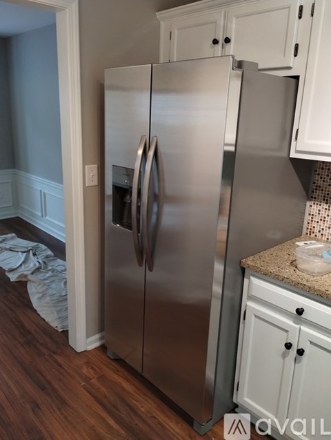 A stainless steel refrigerator in a kitchen with white cabinets.