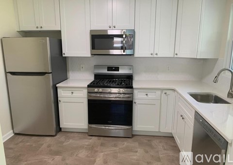 A kitchen with white cabinets and a stainless steel refrigerator.