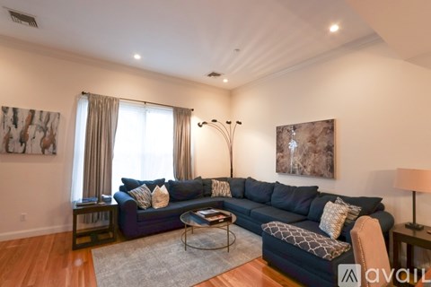 A living room with a dark blue couch and a grey rug.