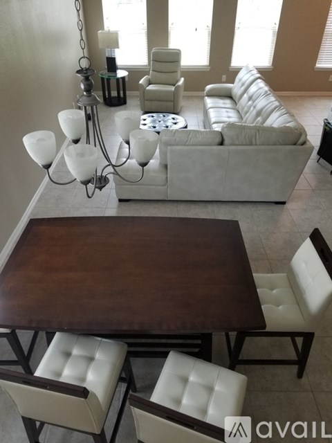 A living room with a brown table and white chairs.