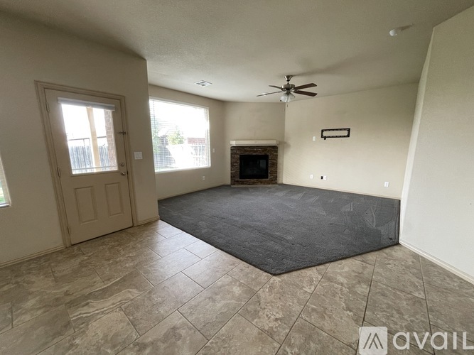 A spacious room with a fireplace and a ceiling fan.