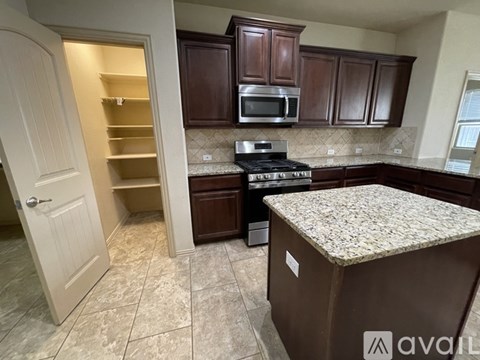 A kitchen with brown cabinets and a granite countertop.