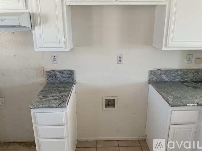 A kitchen with white cabinets and marble countertops.
