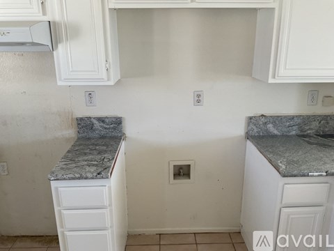 A kitchen with white cabinets and marble countertops.