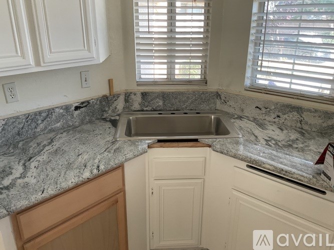 A kitchen with a granite countertop and a stainless steel sink.