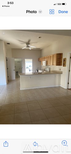A photo of a room with a ceiling fan and a kitchen area.