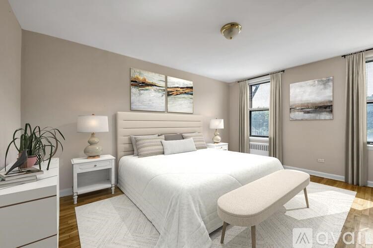 A bedroom with a large bed, a nightstand, and a window with a view of the water.