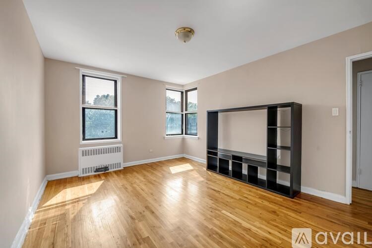 A spacious room with wooden flooring and a large window.