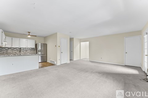 A spacious living room with a kitchen area in the background.
