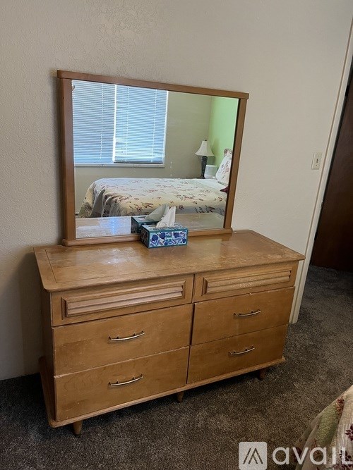A wooden dresser with a mirror on top and a blue box on the dresser.