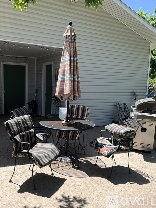 A patio with a table, chairs and an umbrella.
