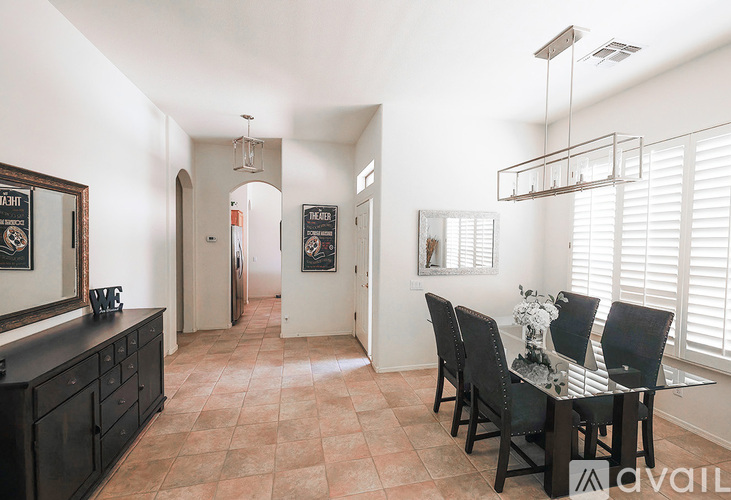 A kitchen with a table and chairs in the foreground and a hallway in the background.