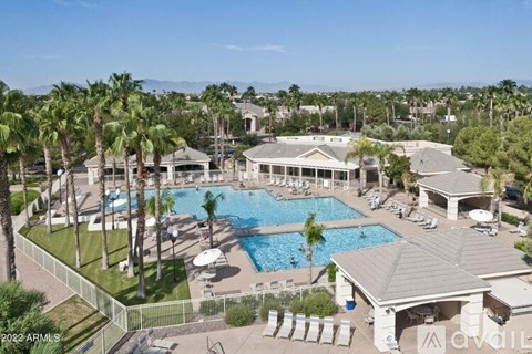 A large outdoor swimming pool surrounded by palm trees and lounge chairs.