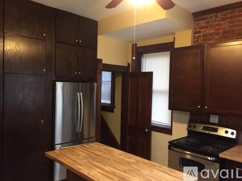 A kitchen with wooden cabinets and a stainless steel refrigerator.