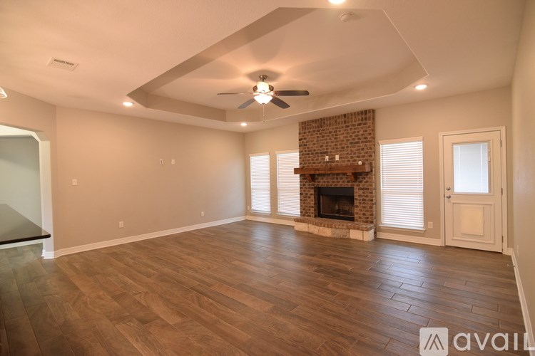 A spacious room with a fireplace and wood flooring.