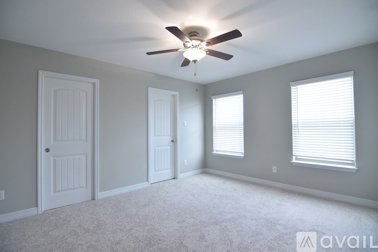 A room with a ceiling fan and three windows.