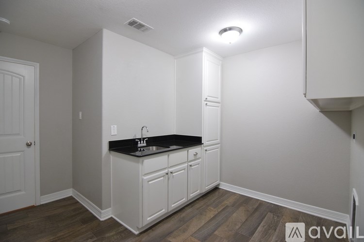A kitchen with white cabinets and a black countertop.