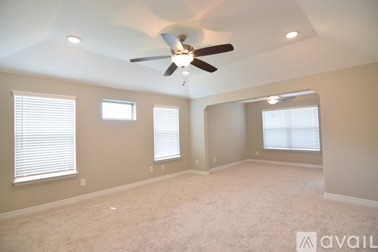 A room with a ceiling fan and three windows.