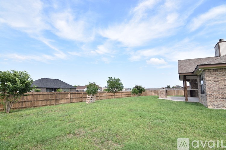 A backyard with a wooden fence and a house in the background.