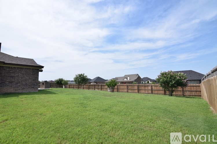 A grassy field with a wooden fence and houses in the background.