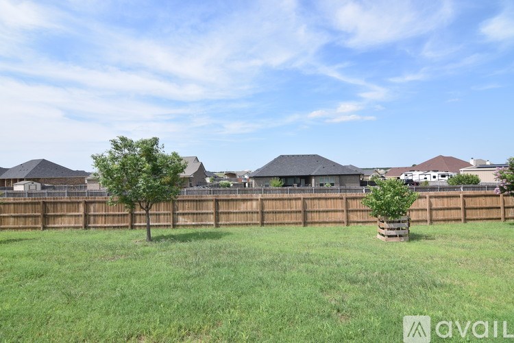 A grassy field with a fence and two trees in the foreground.