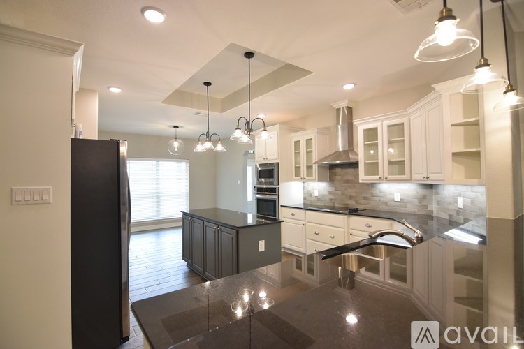 A modern kitchen with a black refrigerator and a marble countertop.