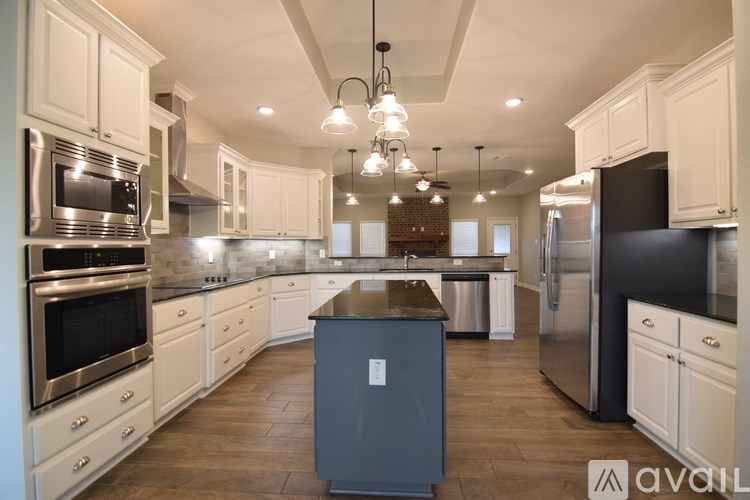 A kitchen with a black refrigerator and white cabinets.