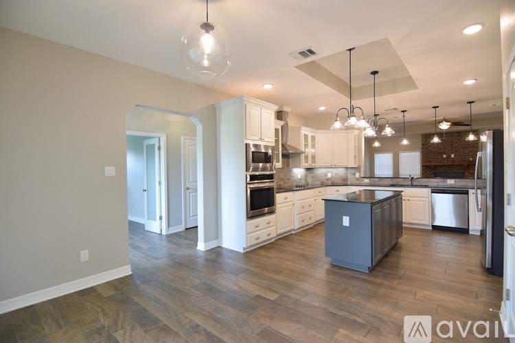 A modern kitchen with a large island and pendant lights.
