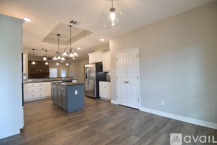 A kitchen with a refrigerator, cabinets, and a countertop with a sink.