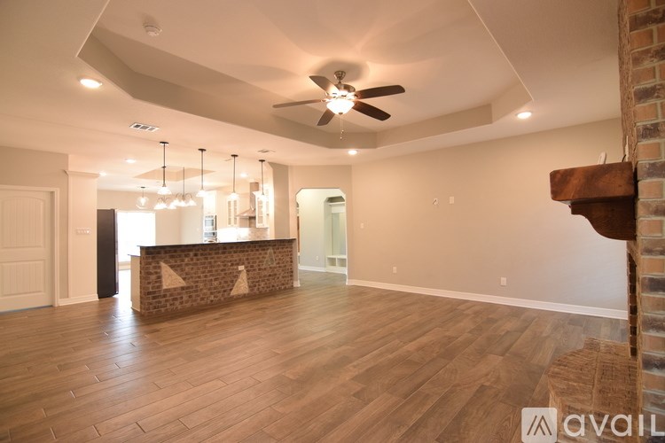 A spacious room with wooden flooring and a ceiling fan.