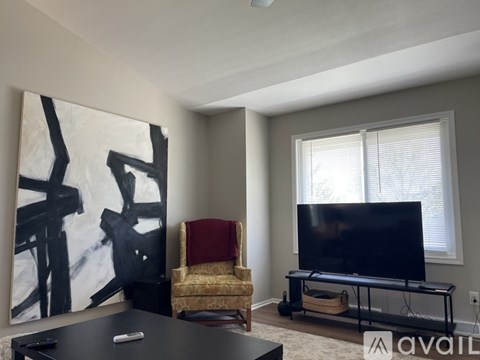 A living room with a television, a chair, and a painting on the wall.