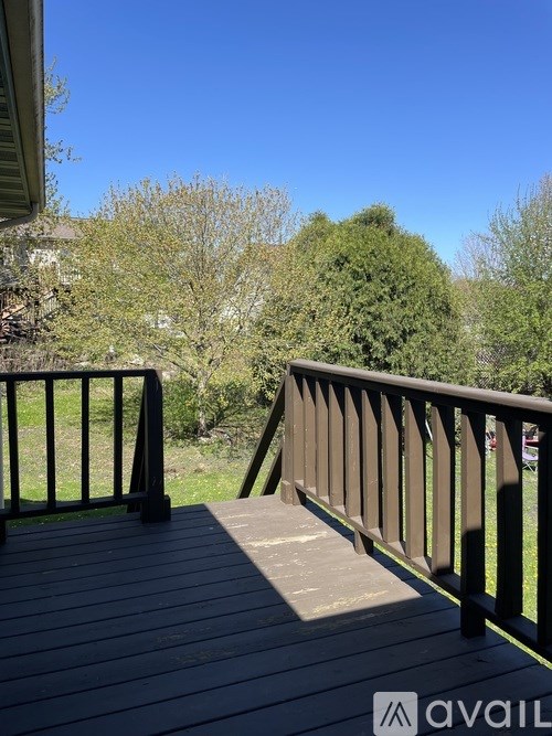 A wooden deck with a railing and trees in the background.