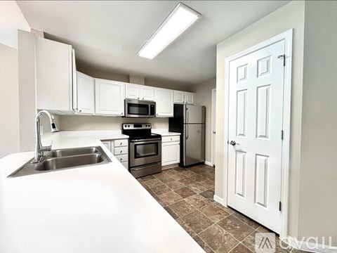 A kitchen with white cabinets and a white door.