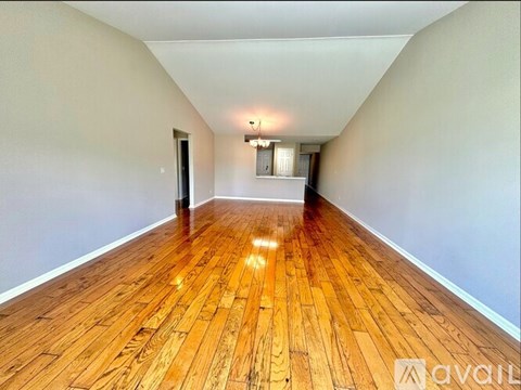 A long hallway with wooden floors and a light on the wall.