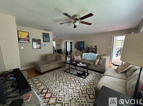 A living room with a patterned carpet and a ceiling fan.