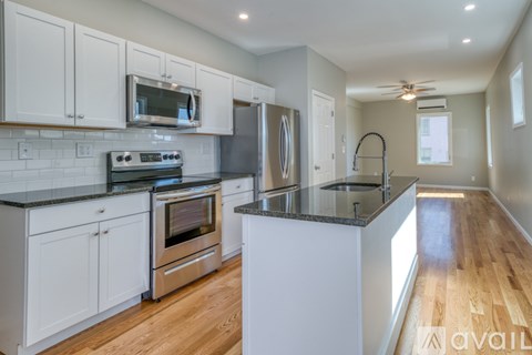 A kitchen with white cabinets and a black countertop.