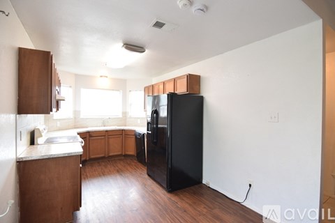 A kitchen with a black fridge and wooden cabinets.