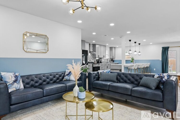 A living room with a black leather sofa and a gold coffee table.