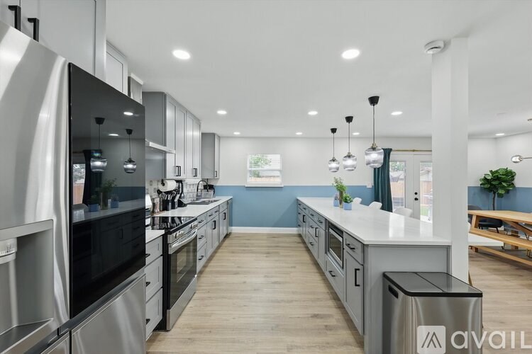 A modern kitchen with stainless steel appliances and wooden floors.