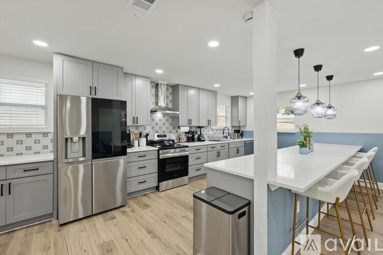 A modern kitchen with stainless steel appliances and wooden floors.