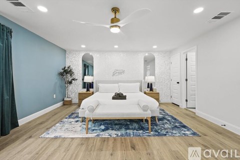A spacious room with a white sofa and a blue rug.