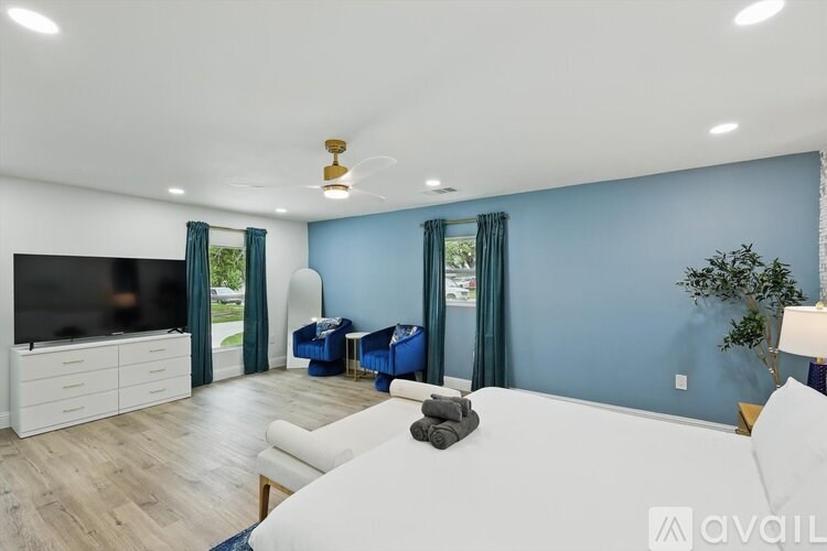 A bedroom with a white bed and a television in the corner.